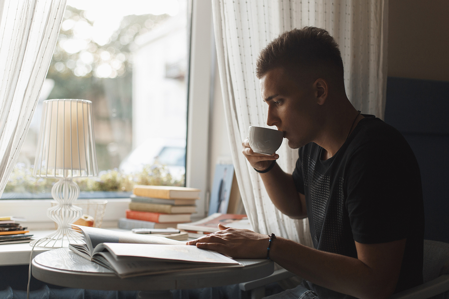 Young Man Rest In A Restaurant, Reading A Book And Drinking Coff