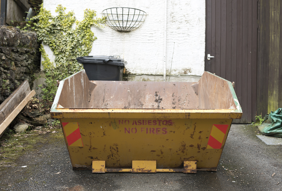 Yellow rubbish skip outdoors in a driveway