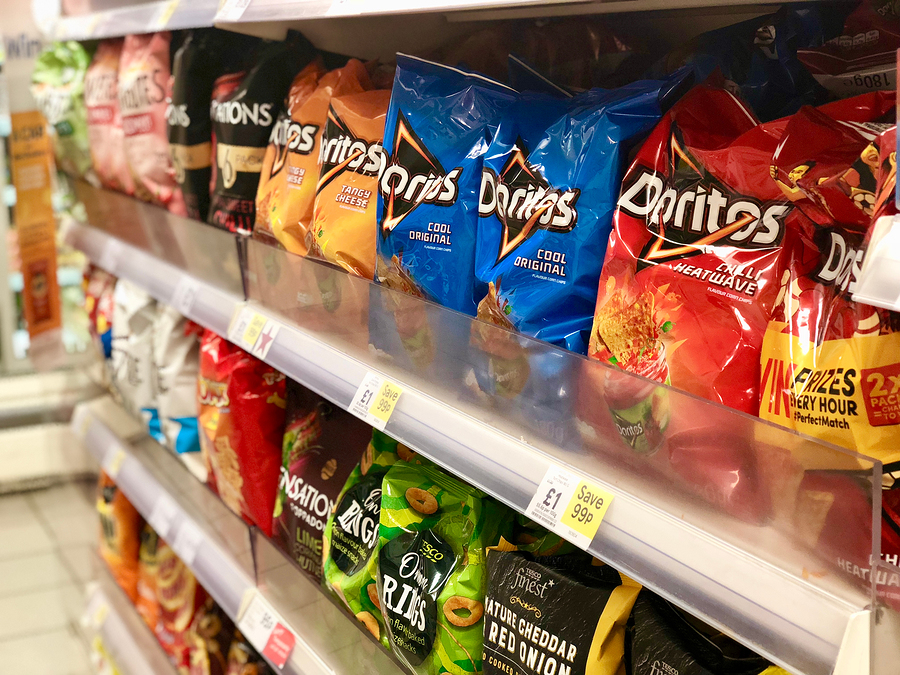 Varieties of potato crisp products on sale on the shelves and in the aisles of Tesco supermarket in London, UK.