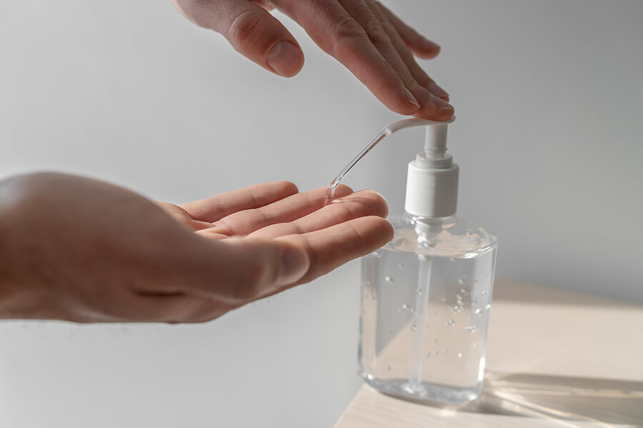 A pair of hands using the hand sanitising pump.