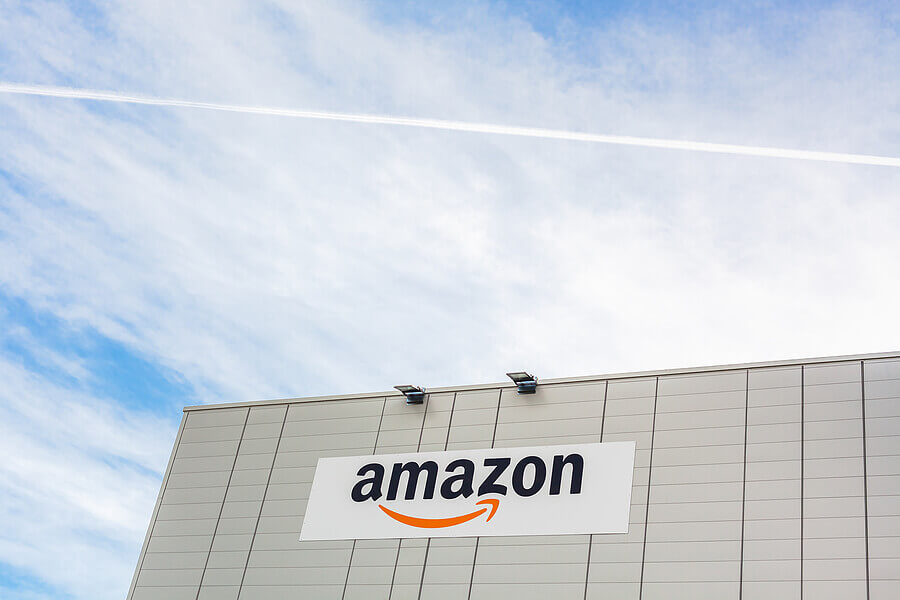Amazon logo on the company warehouse building located in Lyon, France on bright blue sky background with copy space.