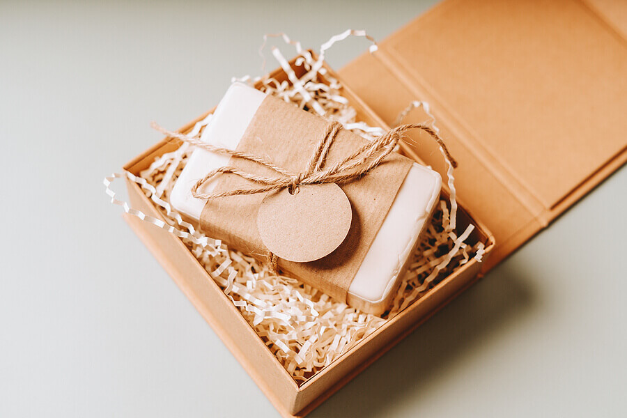 Soap in Craft eco Gift box or present box with bow on gray background with mockup label tag.