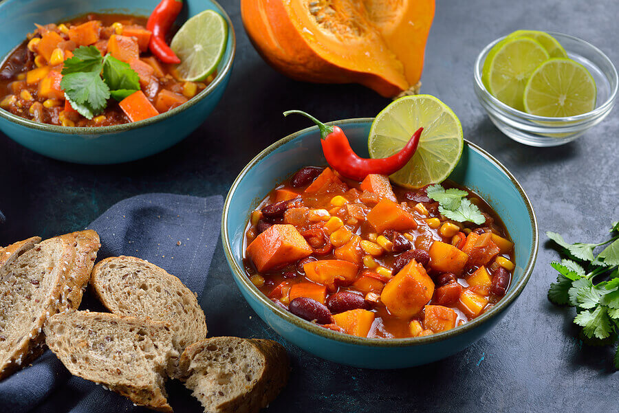 Hot vegan chili with Hokkaido pumpkin from the vegan cuisine with lime and coriander served with slices of a wholemeal roll