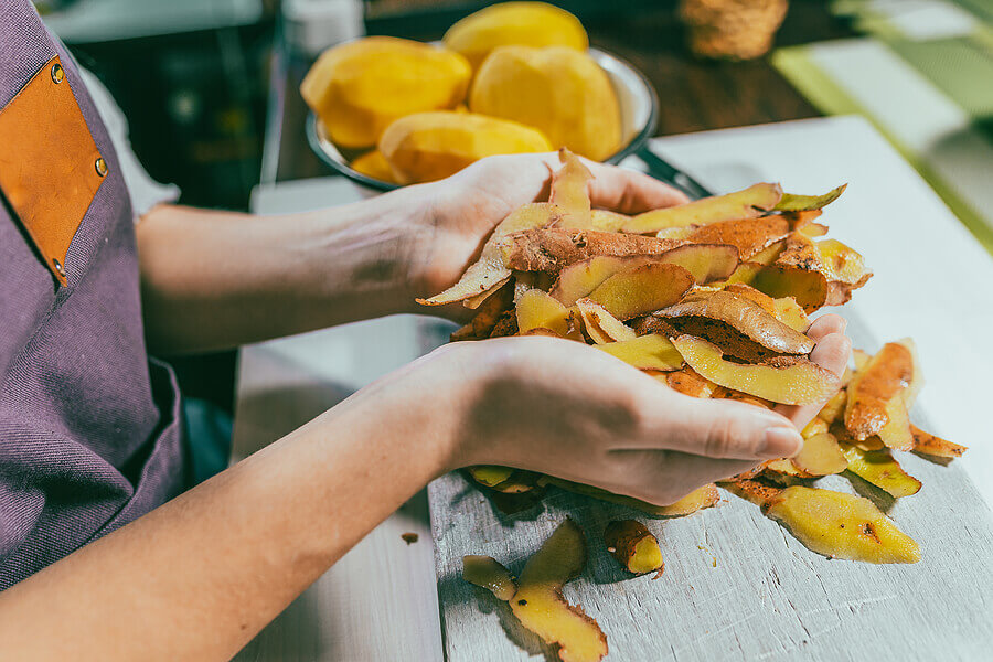 Potato peelings in hands of female cook.