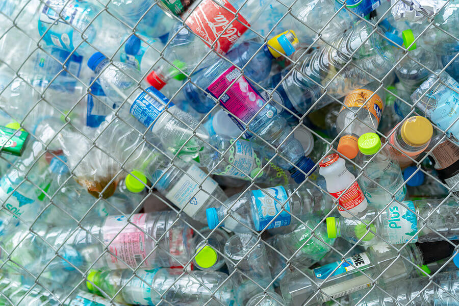 Pile of empty water plastic bottle in mesh fence recycle bin. Plastic bottle waste for recycle in recycling business.