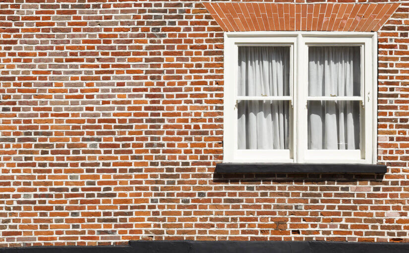 A repointed brick house with a traditional sash window.