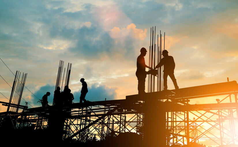 Construction workers working at height on scaffolding at sunrise